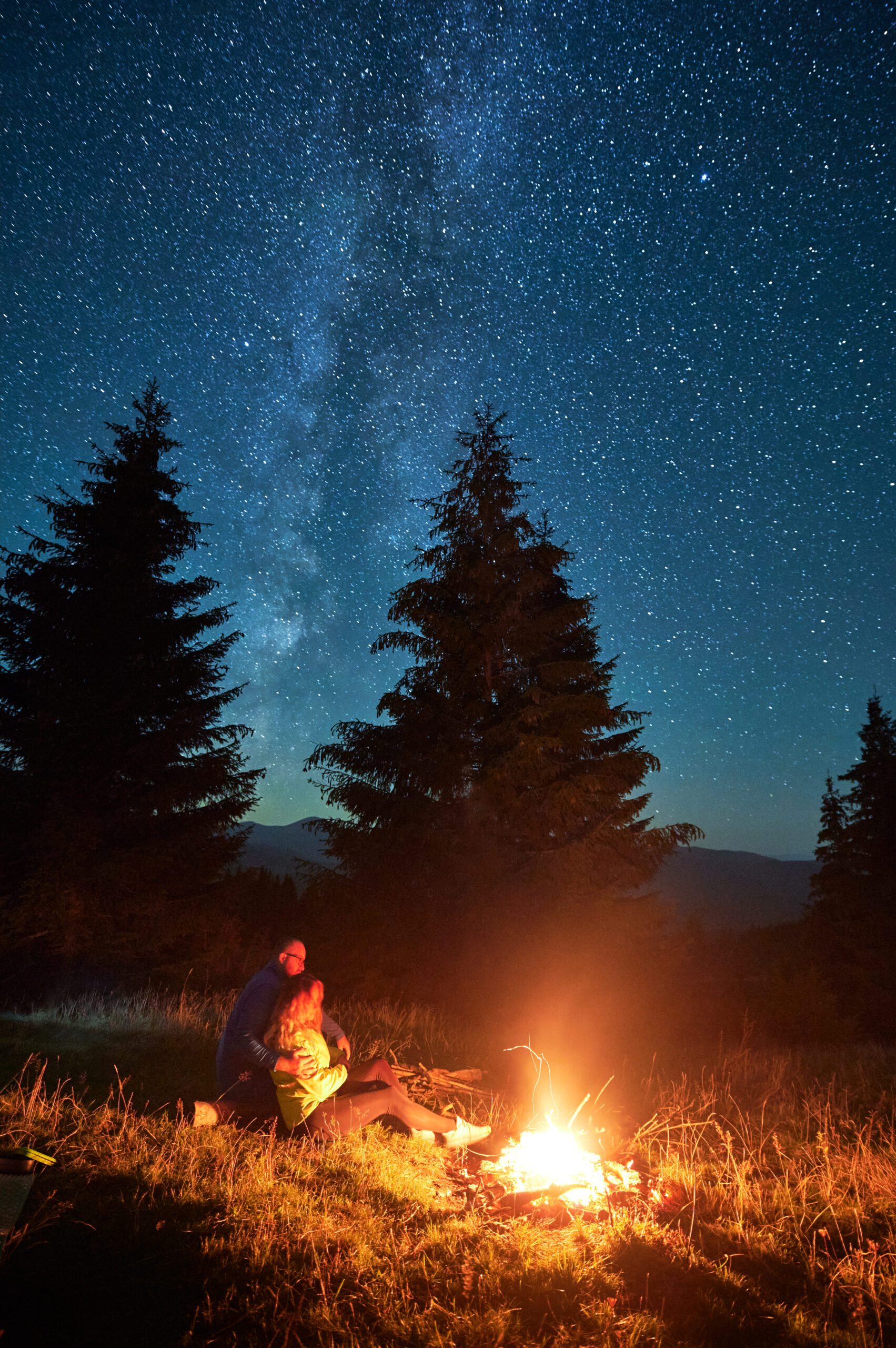 person staring at the constellations by a campfire